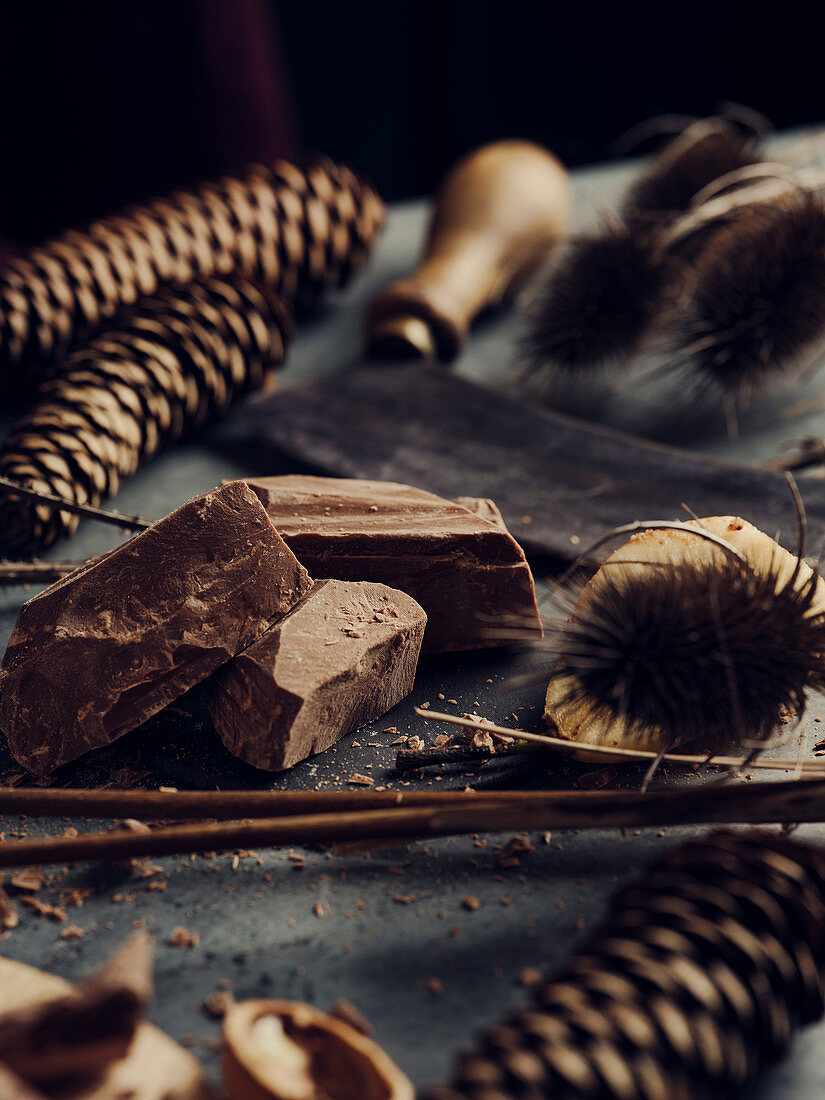 Herbstliches Stillleben mit Schokolade, Nüssen und Zapfen