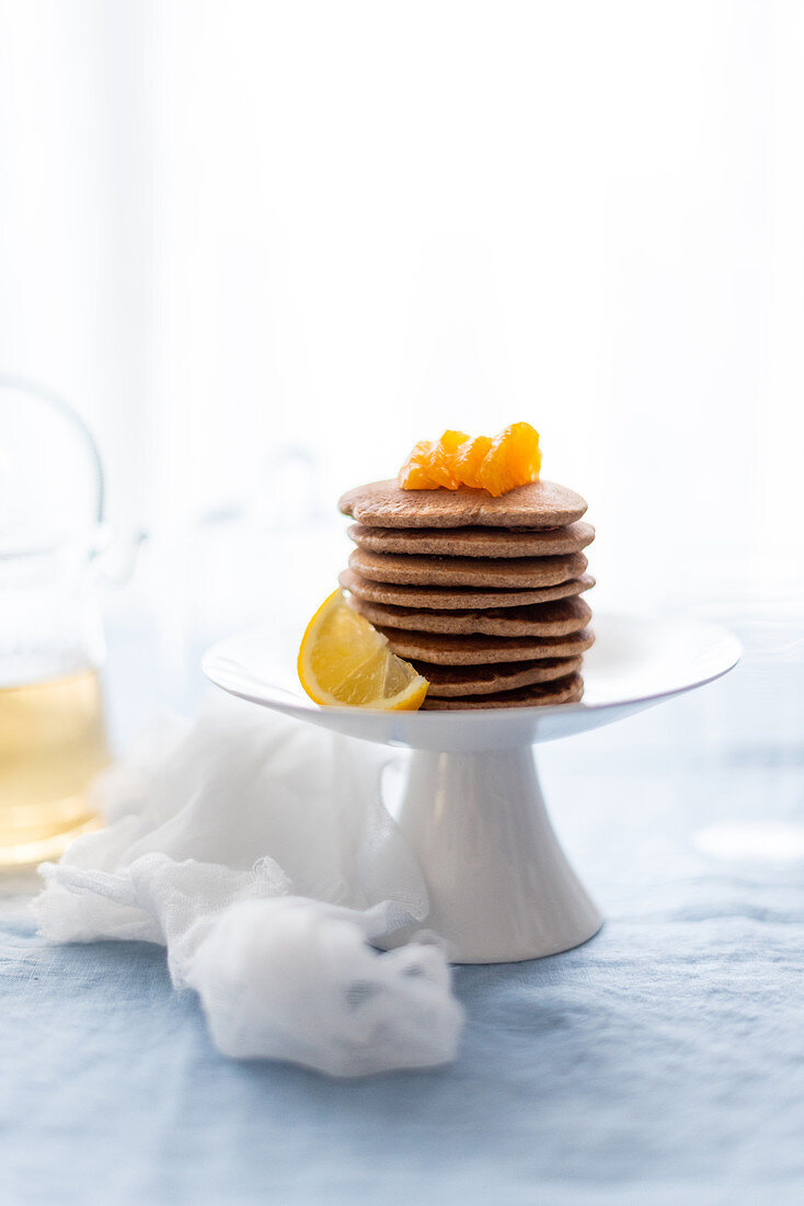 A stack of buckwheat pancakes with citrus fruits