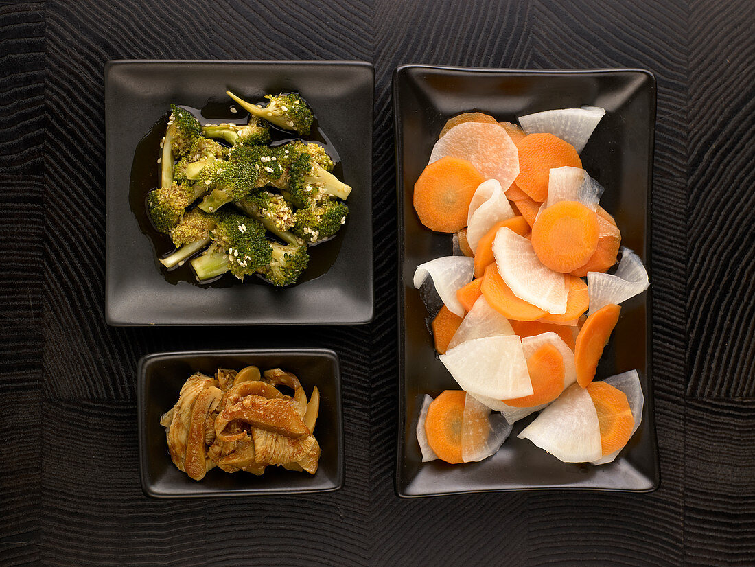Chinesisches Gericht mit Fleisch und Gemüsebeilagen auf seperaten Tellern