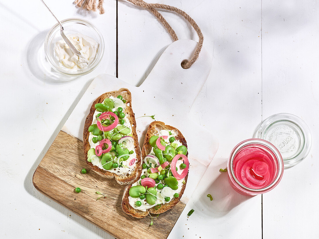 Brot mit Frischkäse, Erbsen, Saubohnen und eingelegten roten Zwiebeln