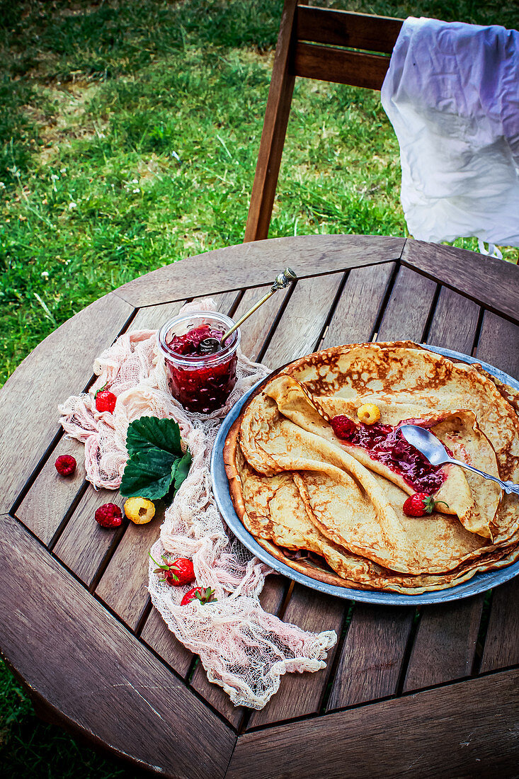 Dinkelpfannkuchen mit Himbeermarmelade auf Gartentisch