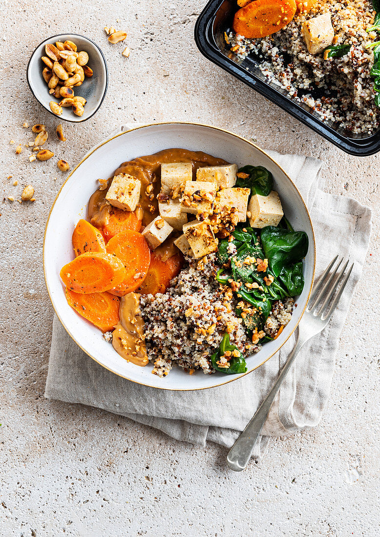Bowl of tofu, carrots, quinoa and spinach with peanut sauce
