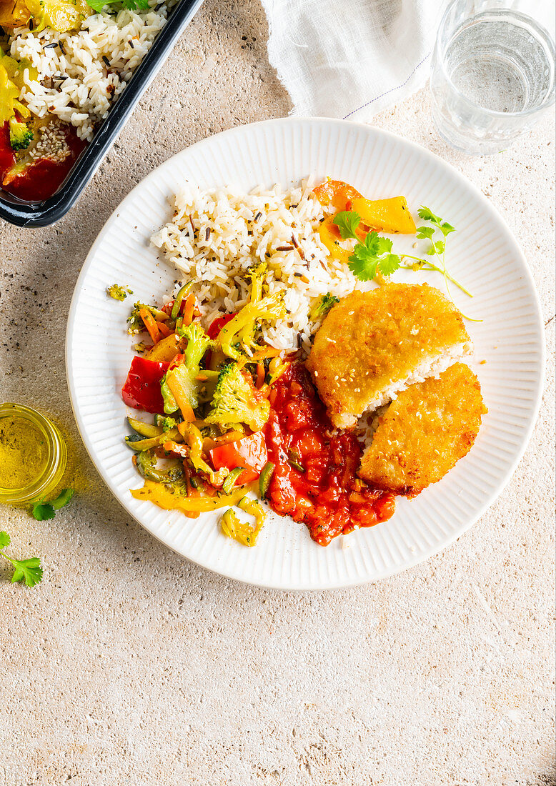 Paniertes Schnitzelchen mit Reis, Gemüse und Tomatensauce