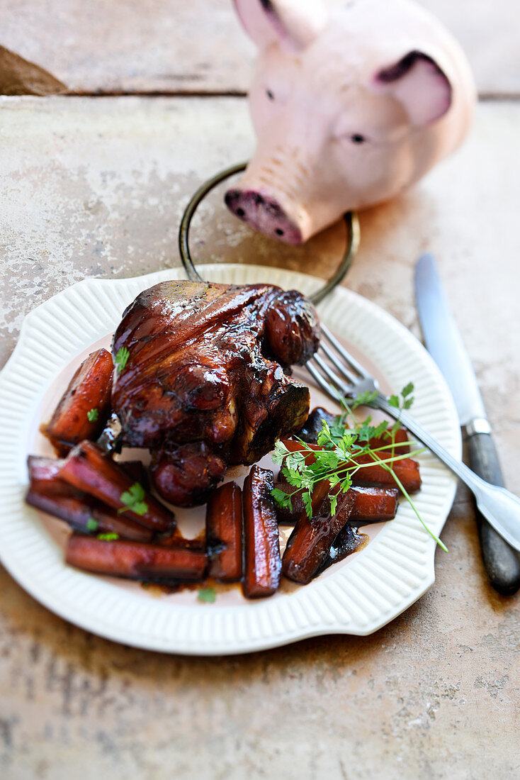 Schweinehaxe glasiert mit Honig und vier Gewürzen serviert mit Karotten