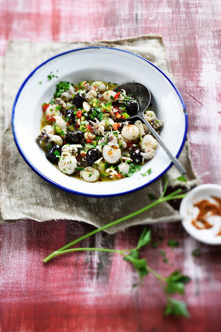 Salat mit mariniertem Tintenfisch, Paprika, Oliven, Knoblauch und Kräutern