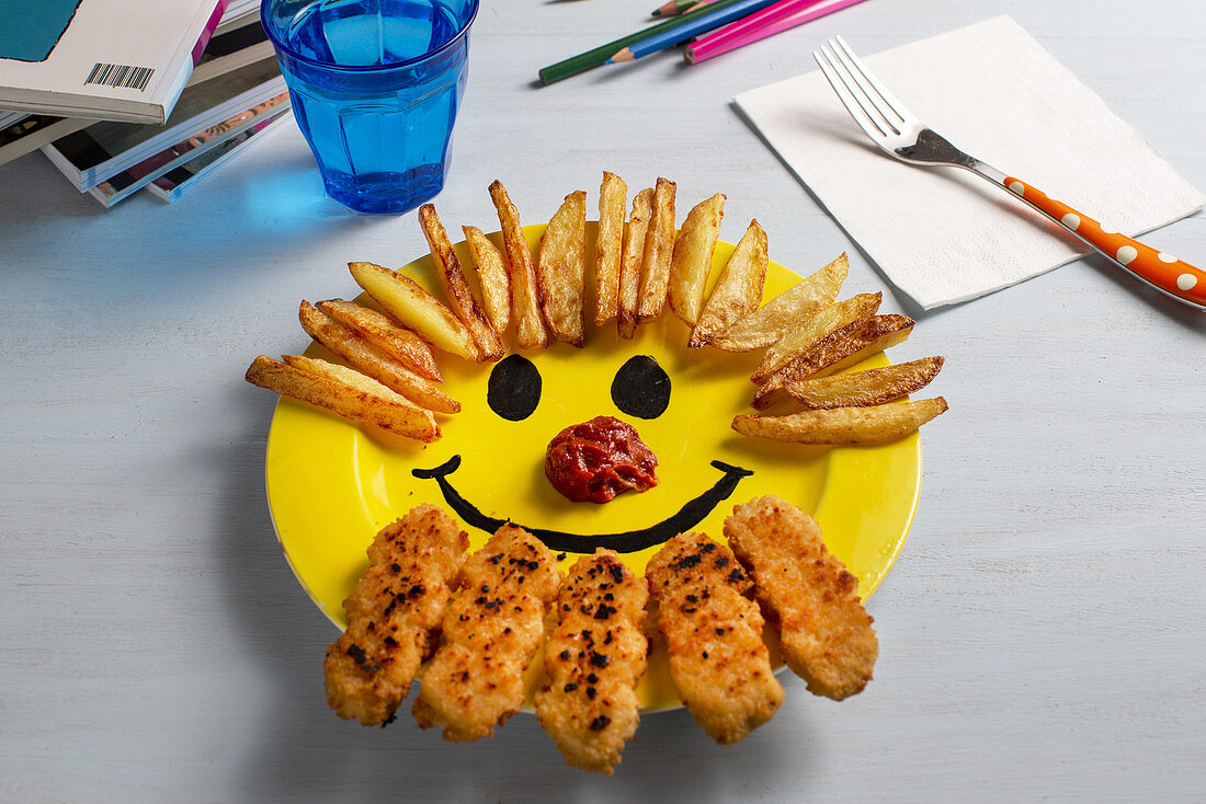 Child's menu with french fries, nuggets and ketchup on a yellow plate with a smiley.