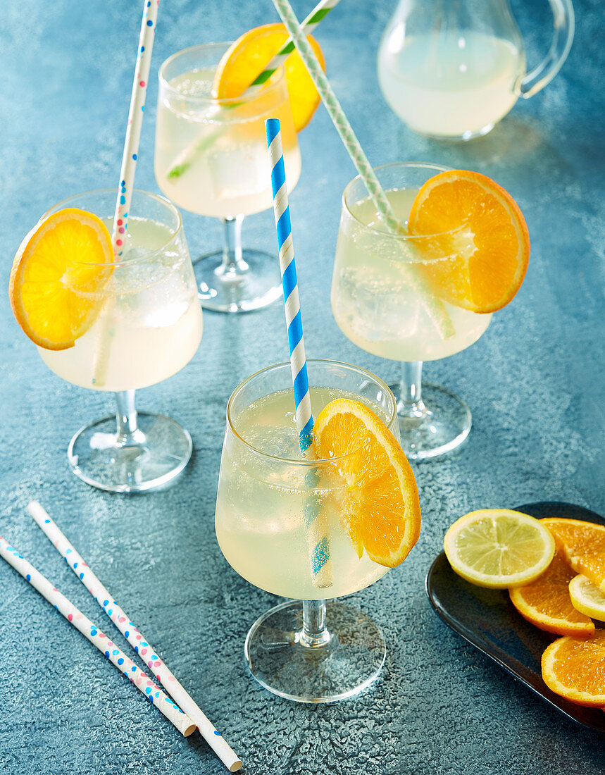 Champagner-Cocktail mit Orangenscheiben und Strohhalmen