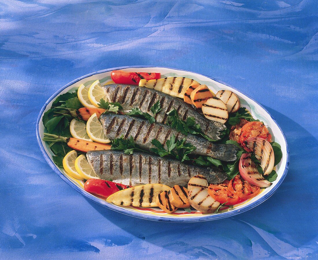 Gegrillte Forellen mit gegrilltem Gemüse auf einer Platte