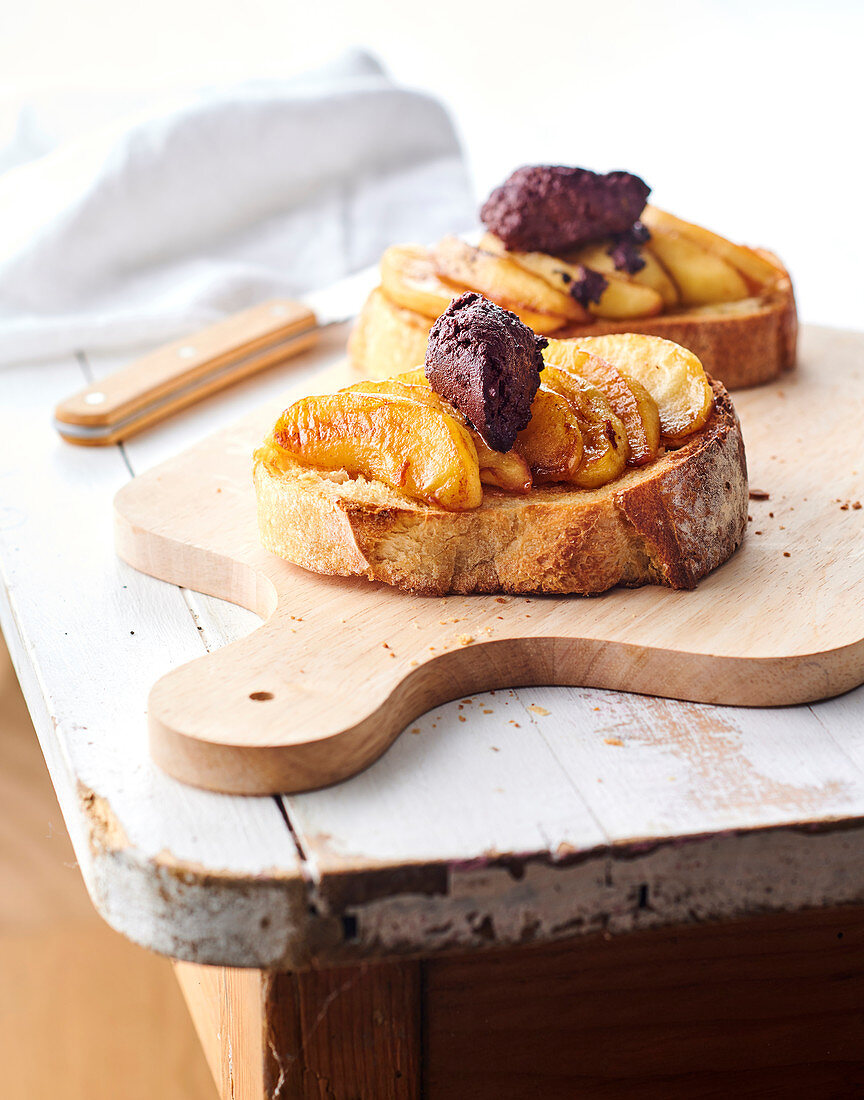 Baguettescheiben belegt mit gebutterten Äpfeln und Blutwurstnocken