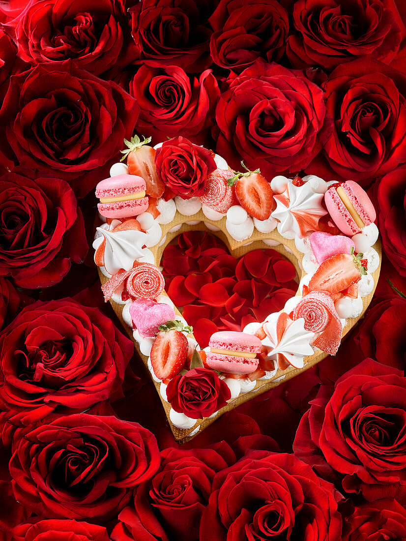 Herzkuchen zum Valentinstags auf Bett aus roten Rosen