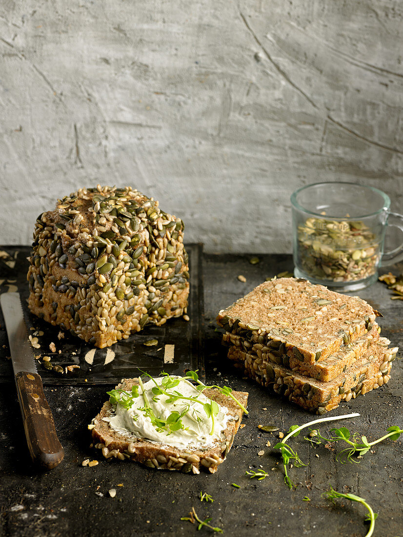 Roggenbrot mit Körnern belegt mit Frischkäse und Kräutern