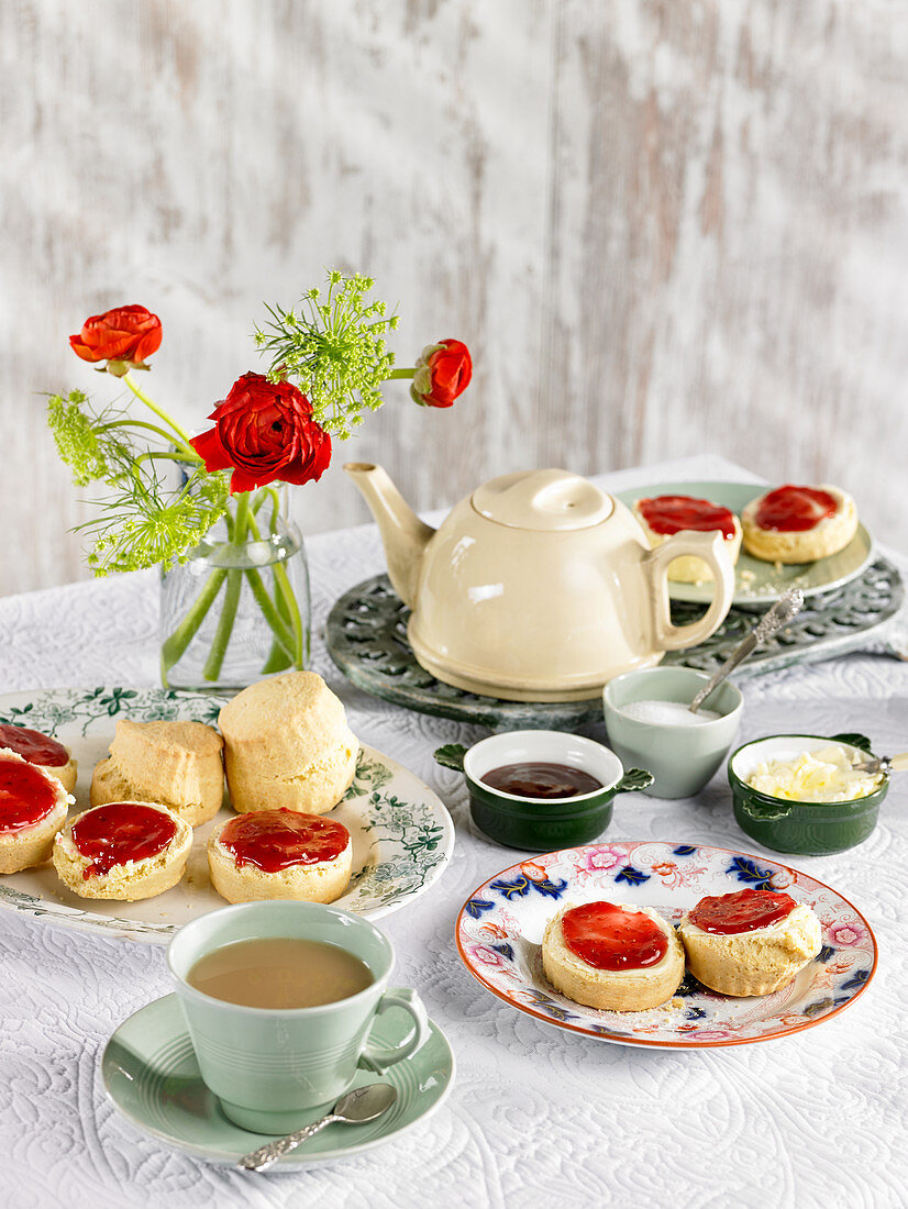 Scones mit Clotted Cream und Marmelade auf gedecktem Tisch