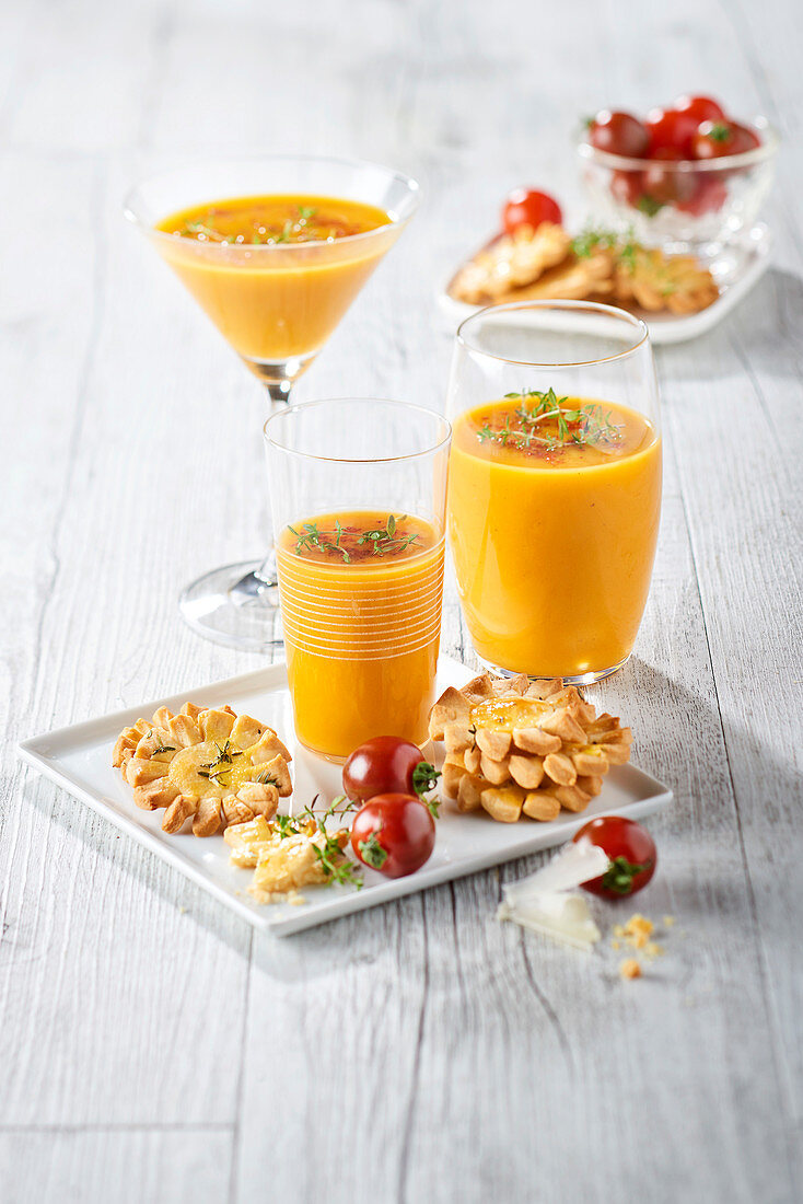 Gelbe Tomaten-Gazpacho in Cocktailgläsern serviert Käsegebäck in Sonnenform