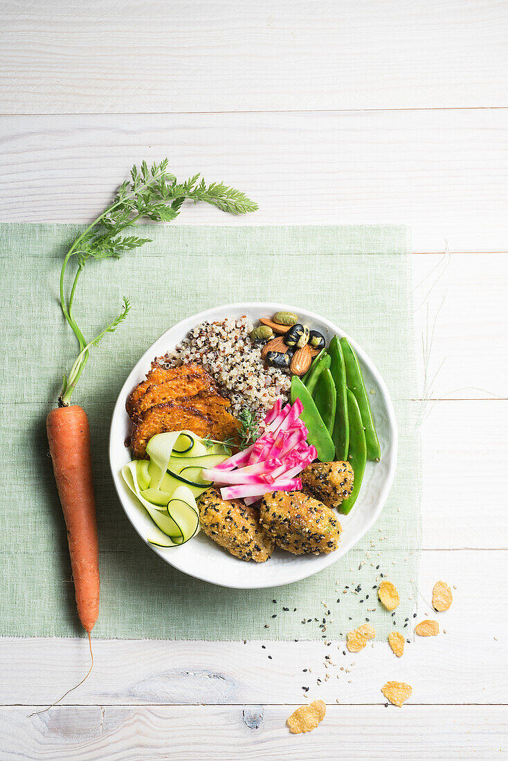 Quinoa-Bowl mit Karottenchips, Krautkroketten, Zucchini-Tagliatelle und Zuckererbsen