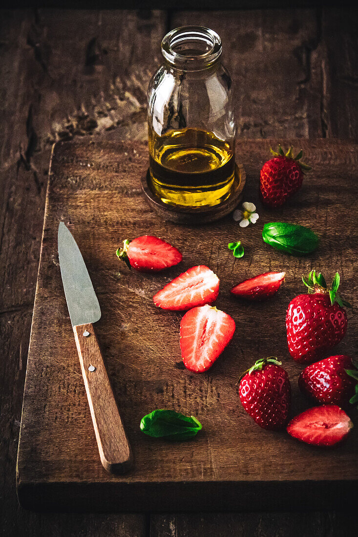 Olivenöl und frische Erdbeeren auf Holzbrett