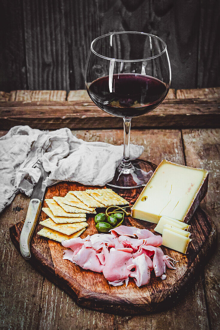 Holzbrett mit Aufschnitt, Käse und einem Glas Rotwein