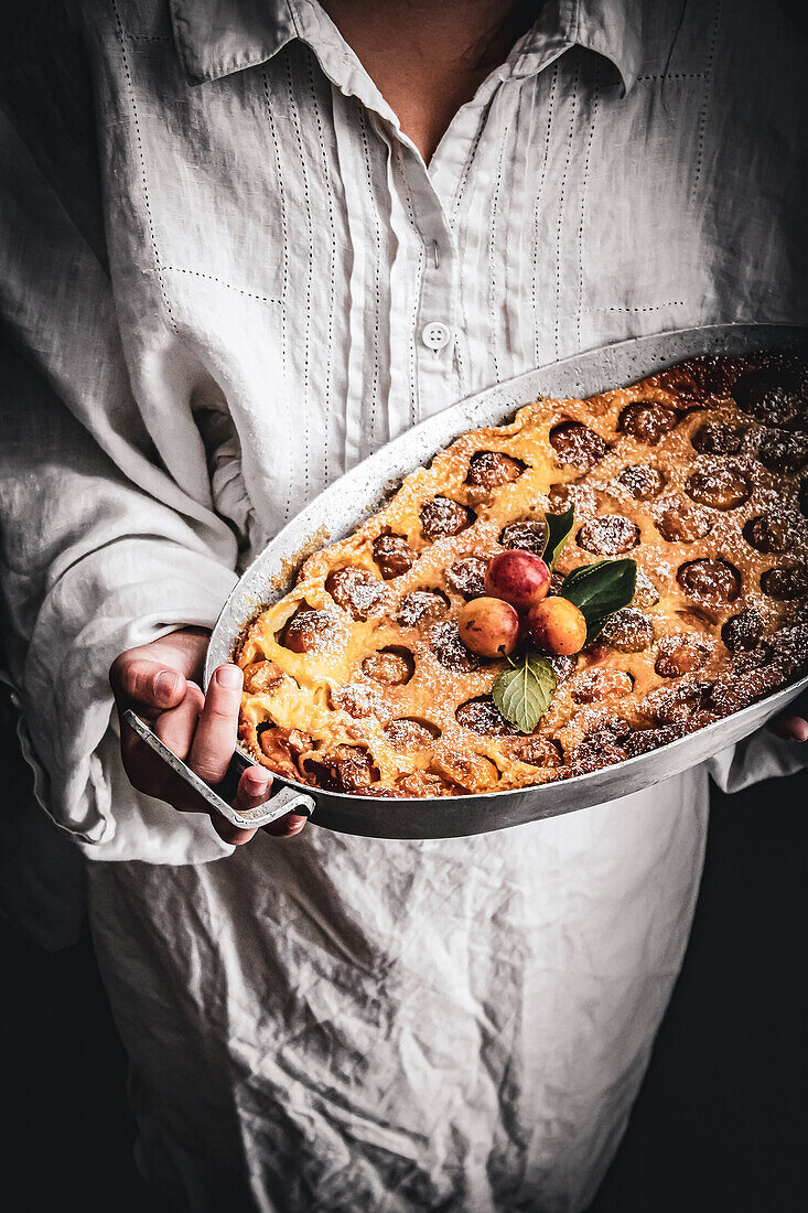 Person hält Clafoutis mit Mirabellen