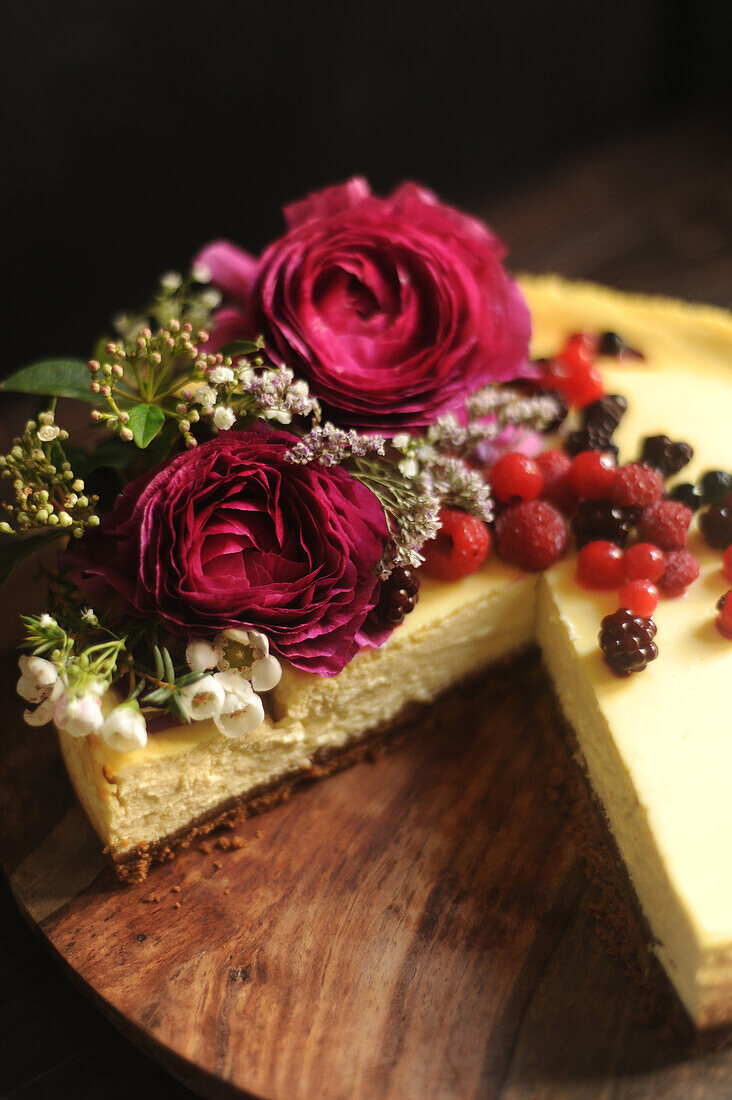 Cheese cake decorated with red berries and rose petals