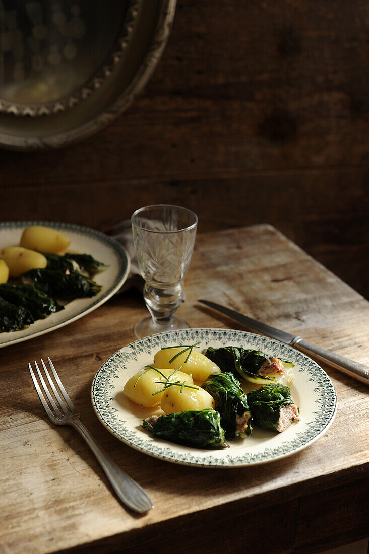 Chard roulades with potatoes on a rustic wooden table