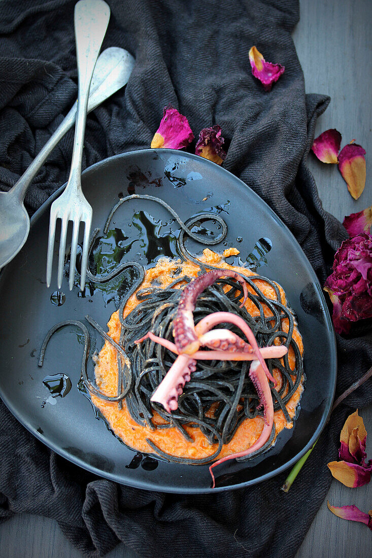 Oktopus-Tentakeln - schwarze Nudeln auf Kürbiscreme zu Halloween