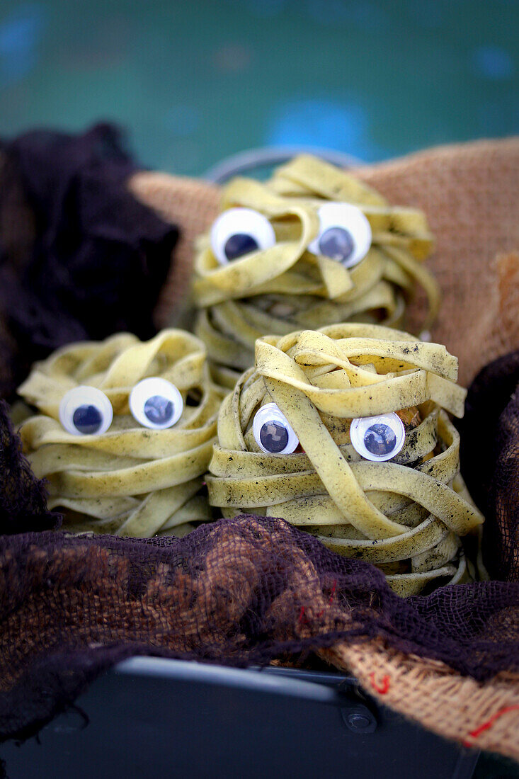 Pasta mummies made of squid tagliatelle for Halloween