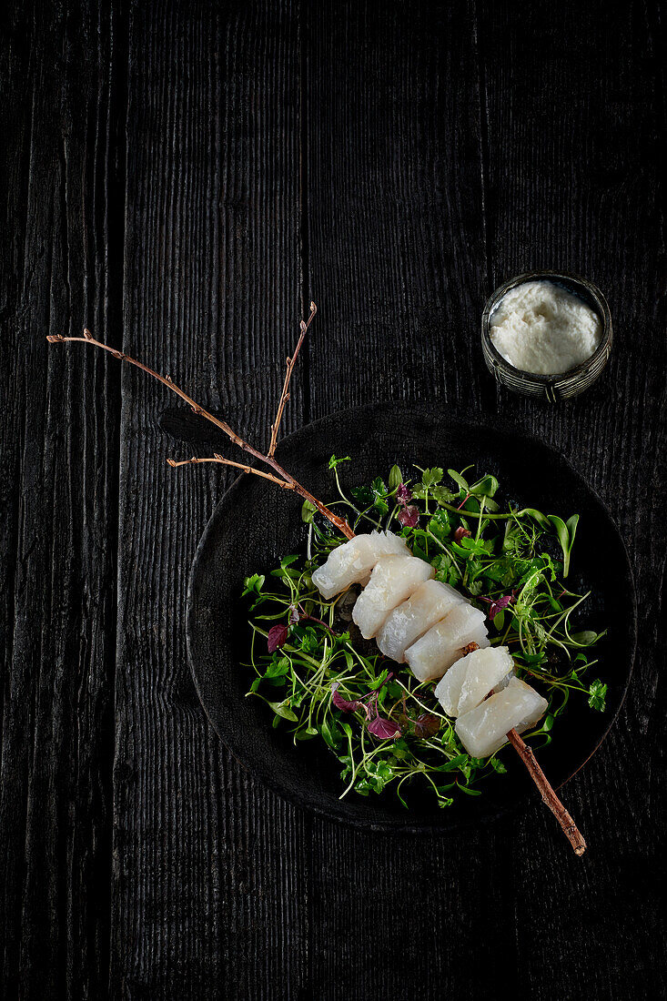 Raw cod skewer on sprouts
