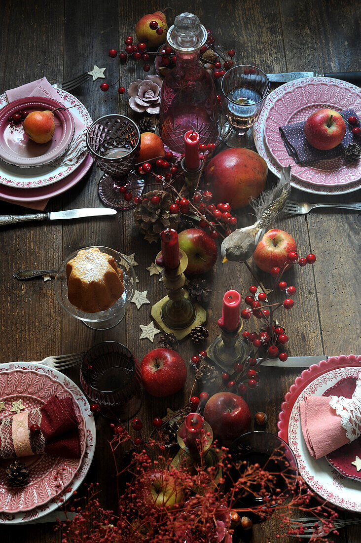 Weihnachtlich gedeckter Tisch dekoriert mit Beerenzweigen, Äpfeln und Kerzen