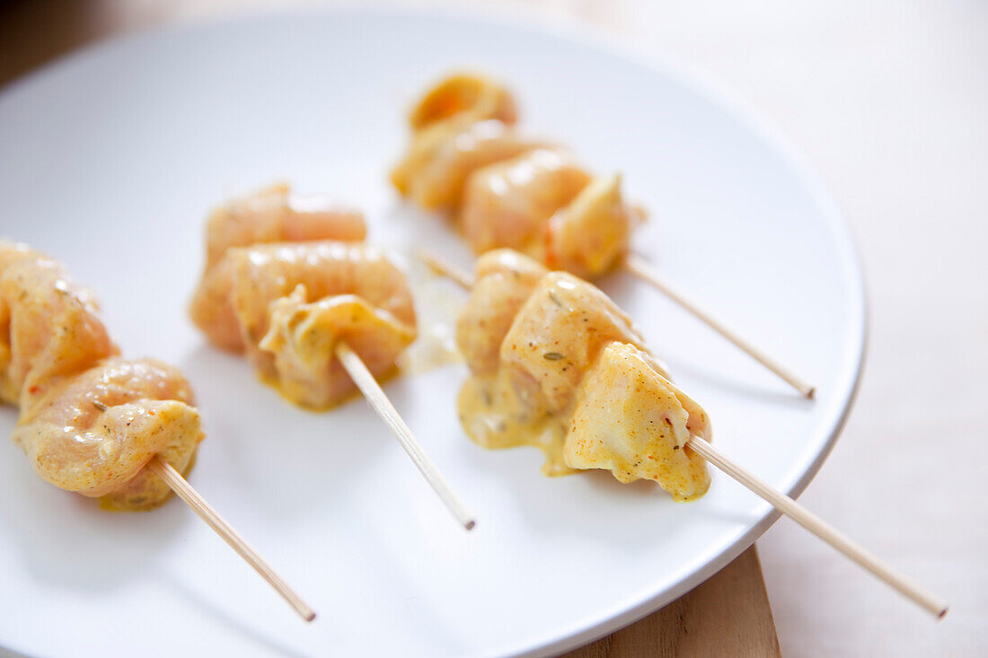 Preparing skewers marinated in coconut milk and curry