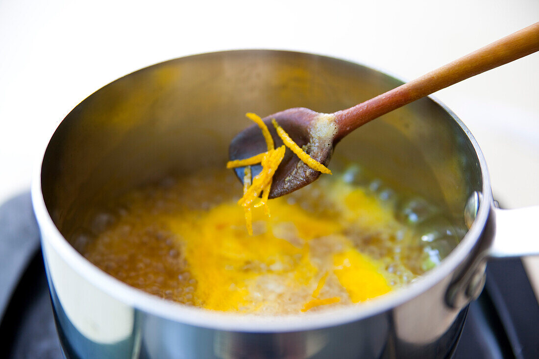 Simmering orange fillets and orange zest in a saucepan