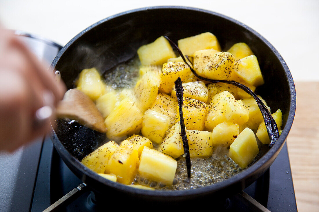 Preparing fried pineapple with butter, vanilla and honey: Fry pineapple chunks in a pan