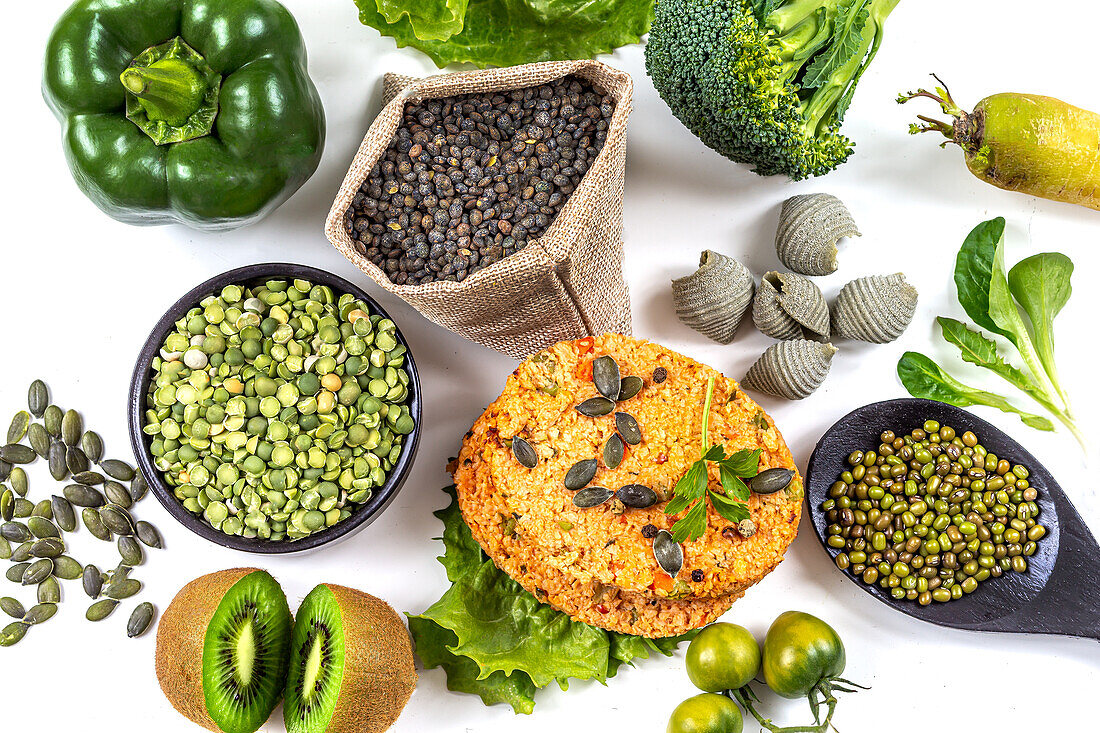 Soy patties surrounded by green vegetables, fruit, legumes, and seeds