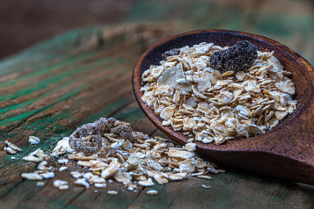 Muesli mix on wooden spoon against a wooden background
