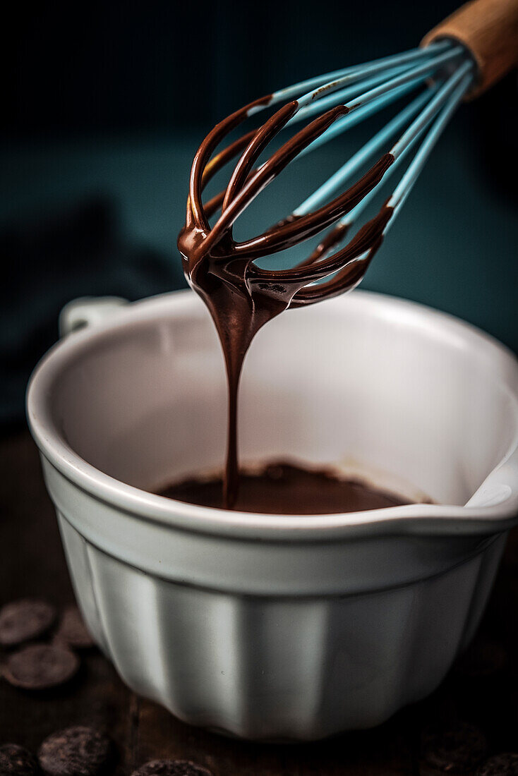 Whisk and small bowl with chocolate sauce