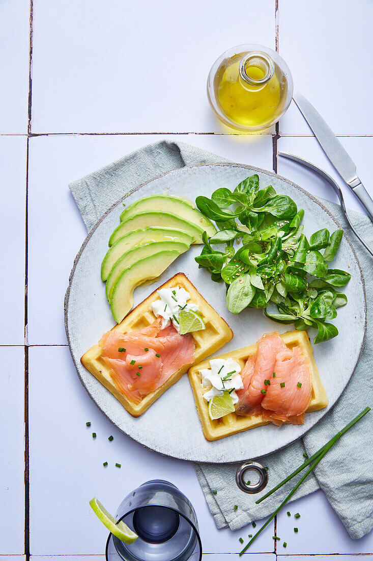 Waffeln mit Räucherlachs serviert mit Avocado und Feldsalat