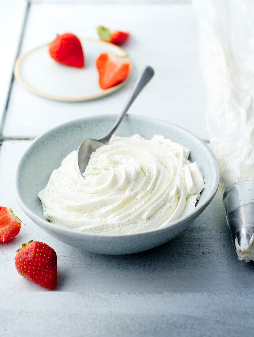 Bowl of whipped cream next to strawberries