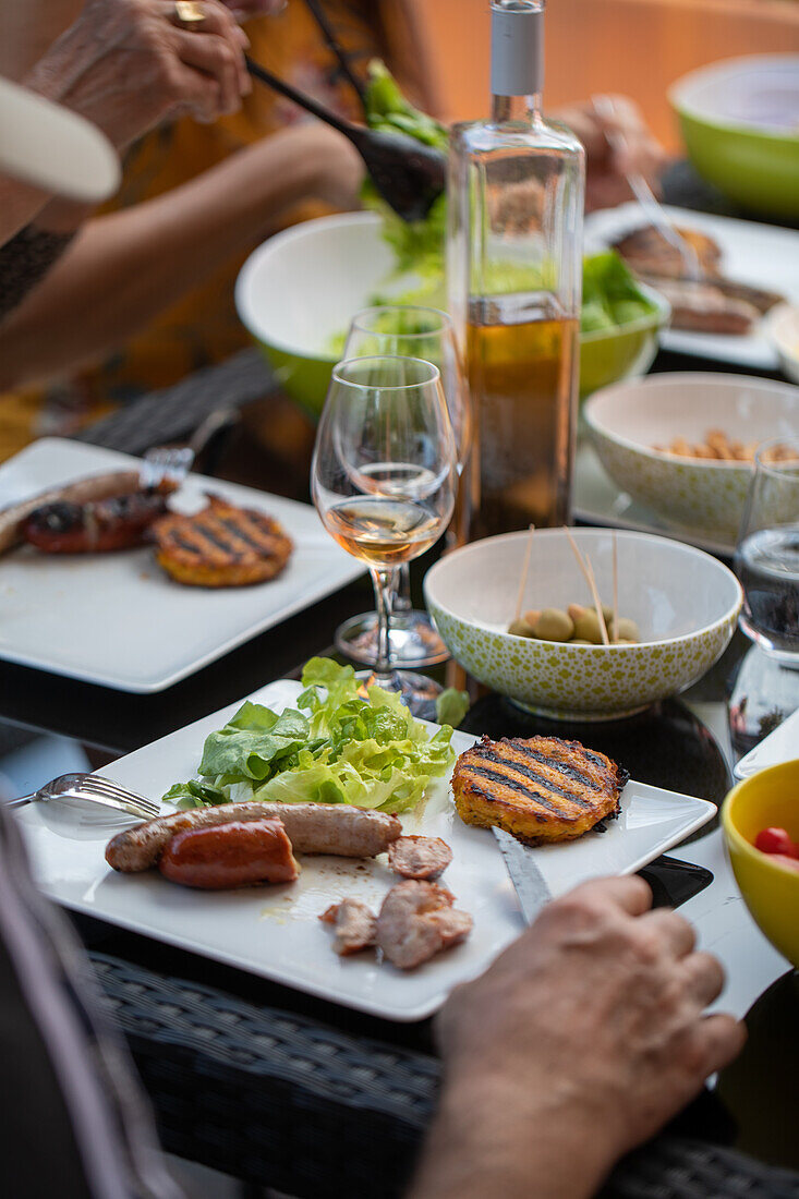 Plate with grilled sausages and lettuce salad on a terrace outdoors
