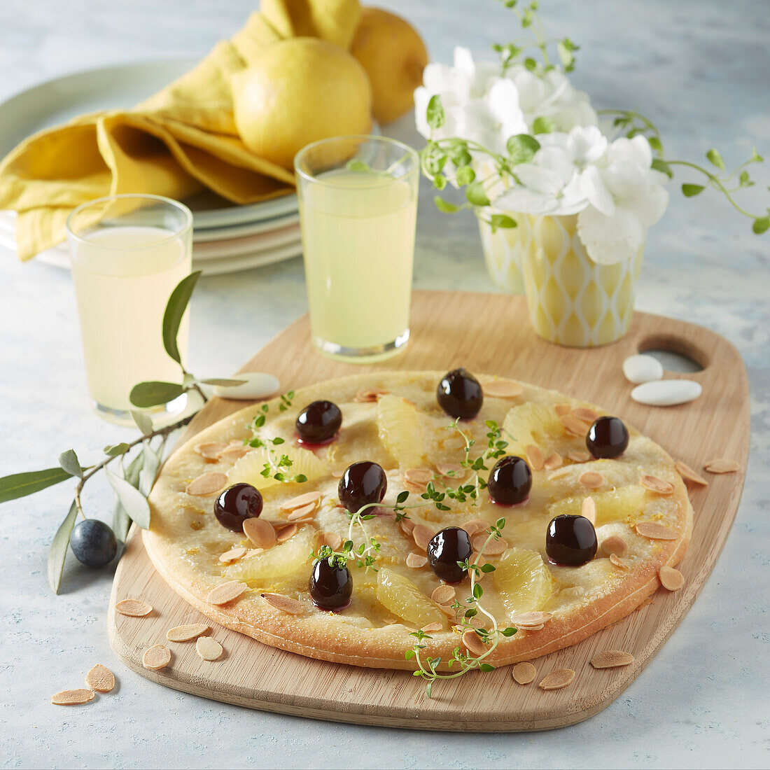 Sweet pizza limoncello with lemon wedges, amarena cherries and almonds