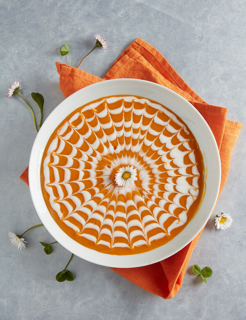 Kürbissuppe mit dekorativem Spinnennetz verziert