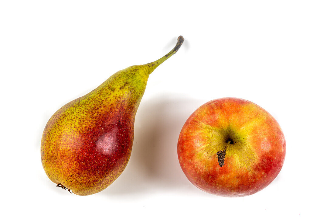 Apfel und Birne nebeneinander auf weißem Untergrund
