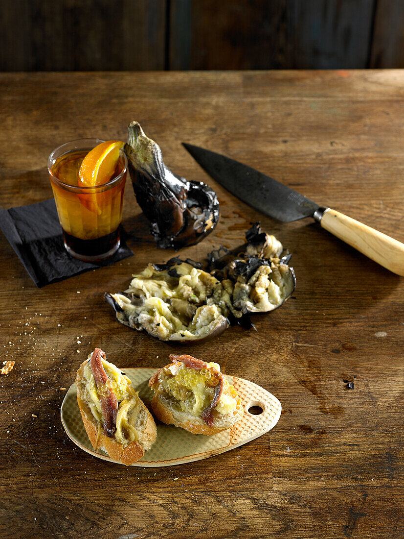 Auberginen-Tapas mit Sardellen, Knoblauch und Petersilie dazu ein Glas Vermouth
