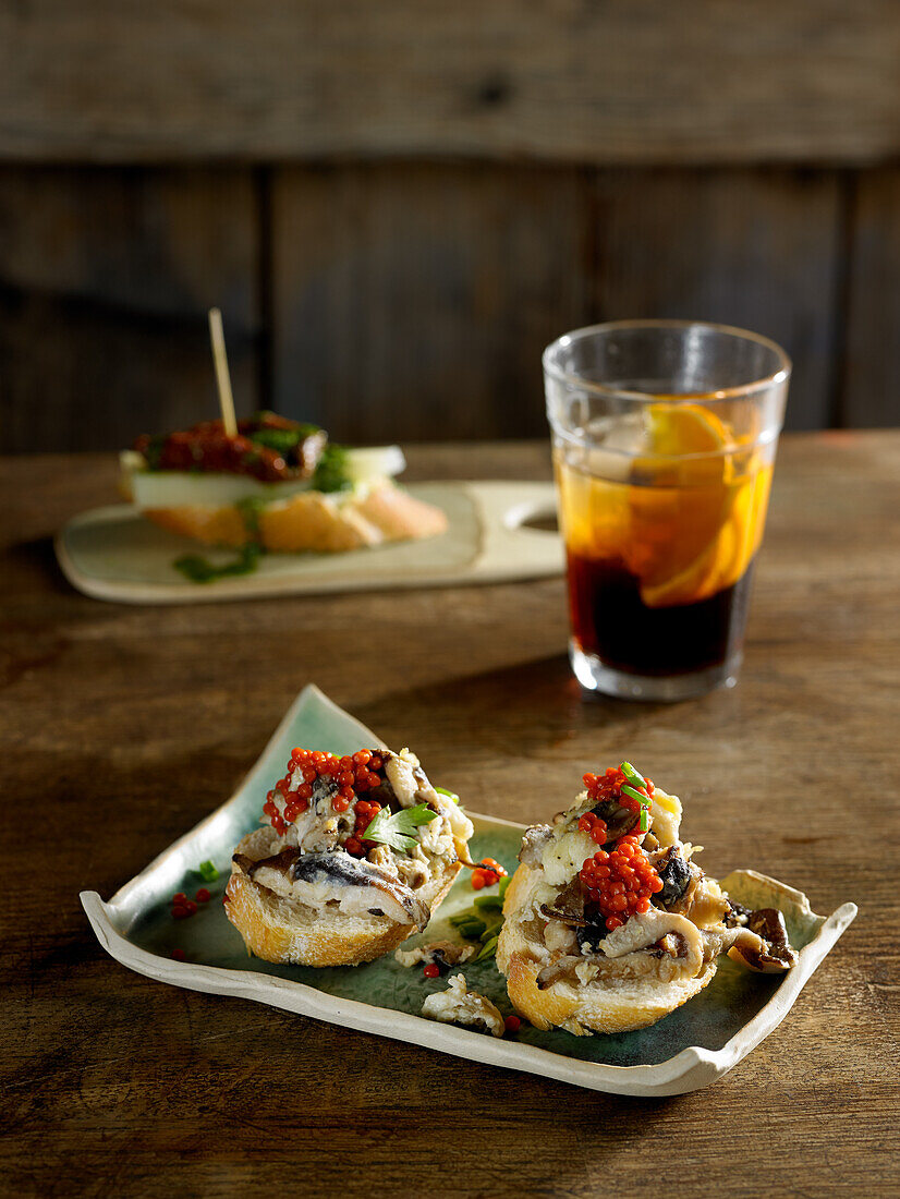 Rührei-Tapas mit Pilzen, Knoblauch, Petersilie, Paprikaperlen und einem Glas Vermouth