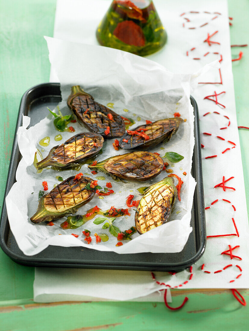 Grilled aubergines on an oven tray with hot chilli oil