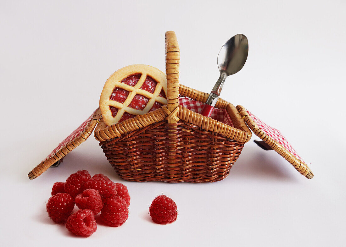 Raspberry tarts and spoons in a miniature picnic basket