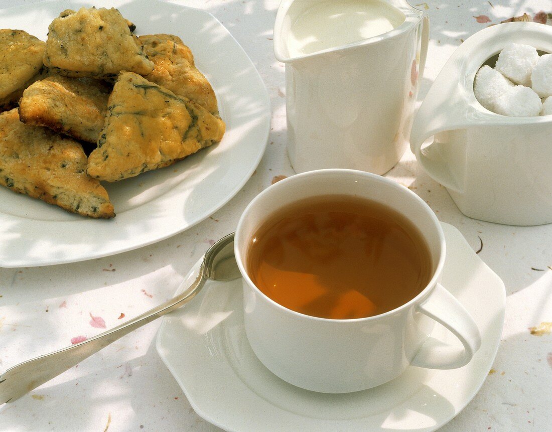 Tee in weisser Tasse, Rosmaringebäck, Milch & Zuckerwürfel