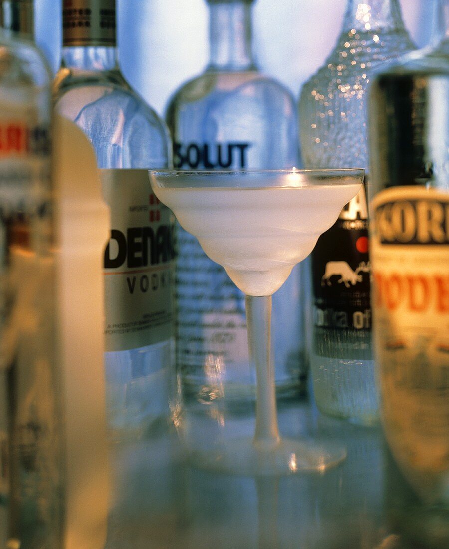 Wodka in Glas vor verschiedenen Wodkaflaschen