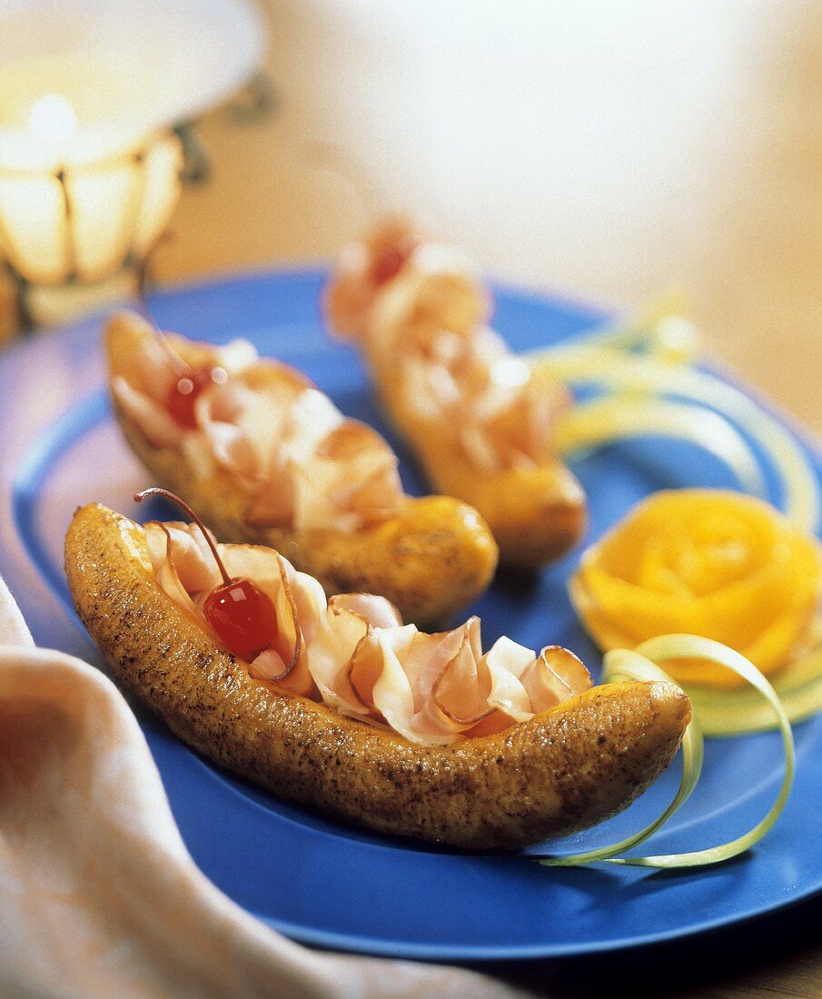 Fried plantains stuffed with ham and cheese with cherry garnish