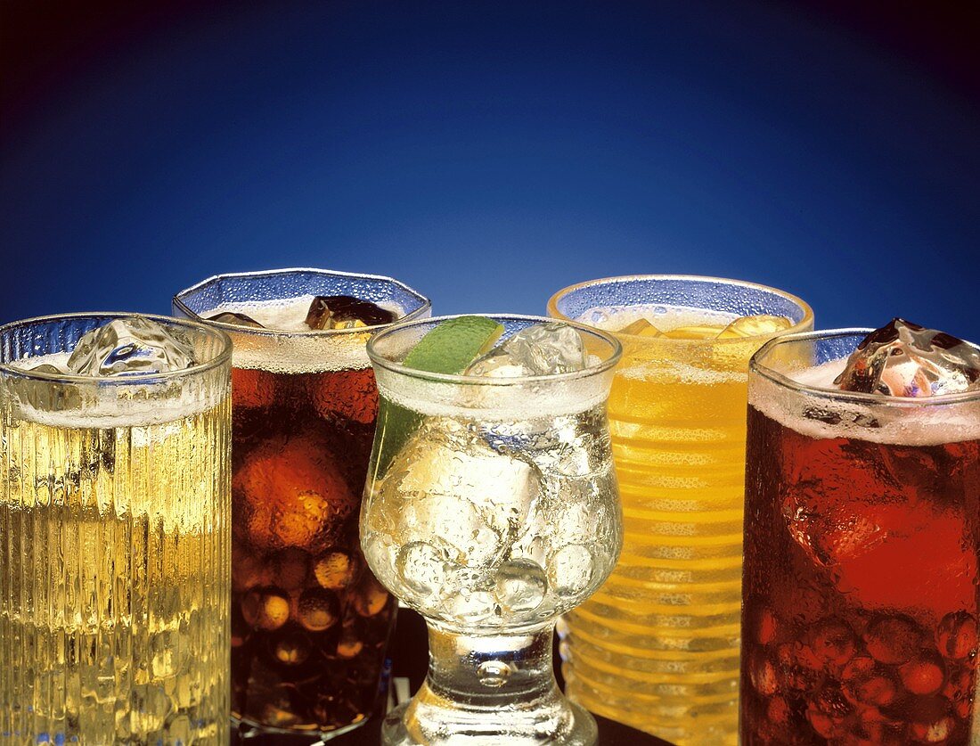 Mehrere bunte Soft Drinks mit Eiswürfeln in Gläsern