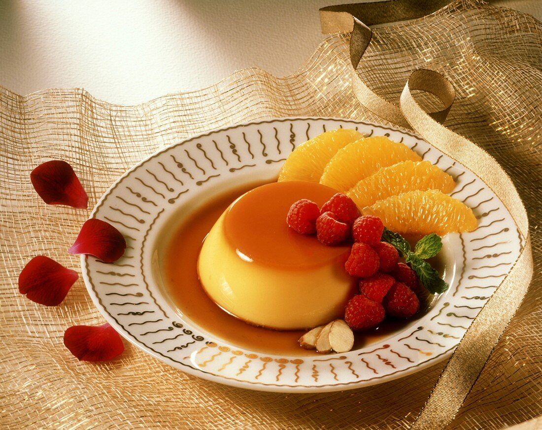 Orange caramel custard with raspberries and orange segments, on a plate