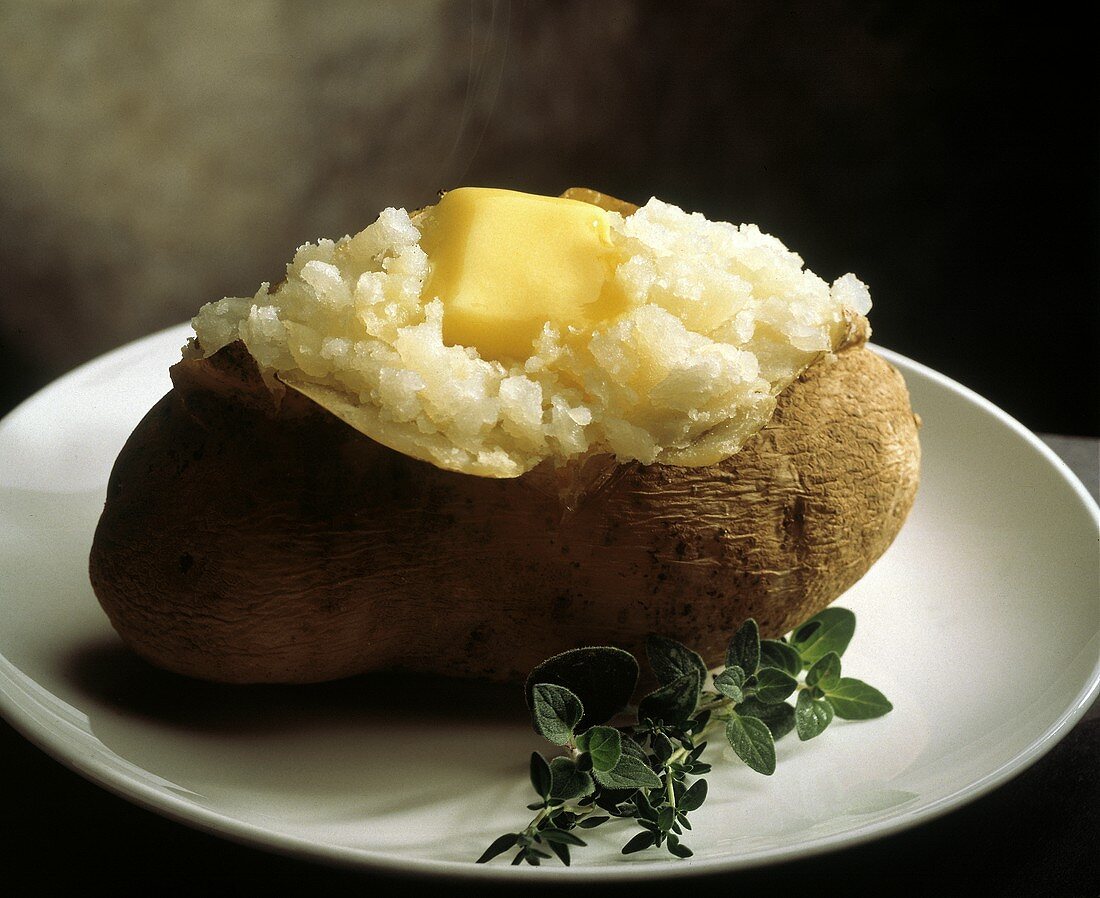 Dampfende Baked Potatoe mit schmelzender Butter auf Teller