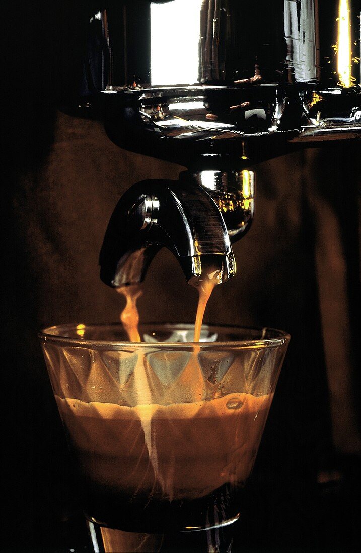 Espresso fliesst aus Espressomaschine in ein Glas